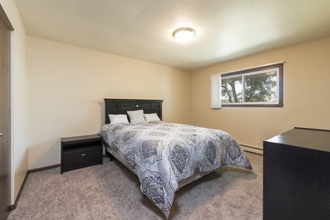 a bedroom with a bed and a window. Bismarck, ND Highland Meadows Apartments