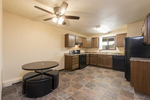 an empty kitchen with a ceiling fan and a table. Bismarck, ND Highland Meadows Apartments