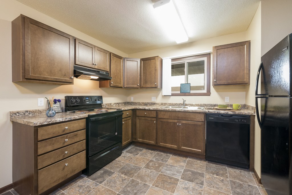 Bismarck, ND Highland Meadows Apartments | Kitchen Bismarck, ND Highland Meadows Apartments. A kitchen with brown cabinets and black appliances