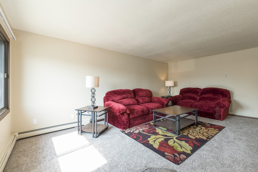 a living room with two couches and a rug. Bismarck, ND Highland Meadows Apartments