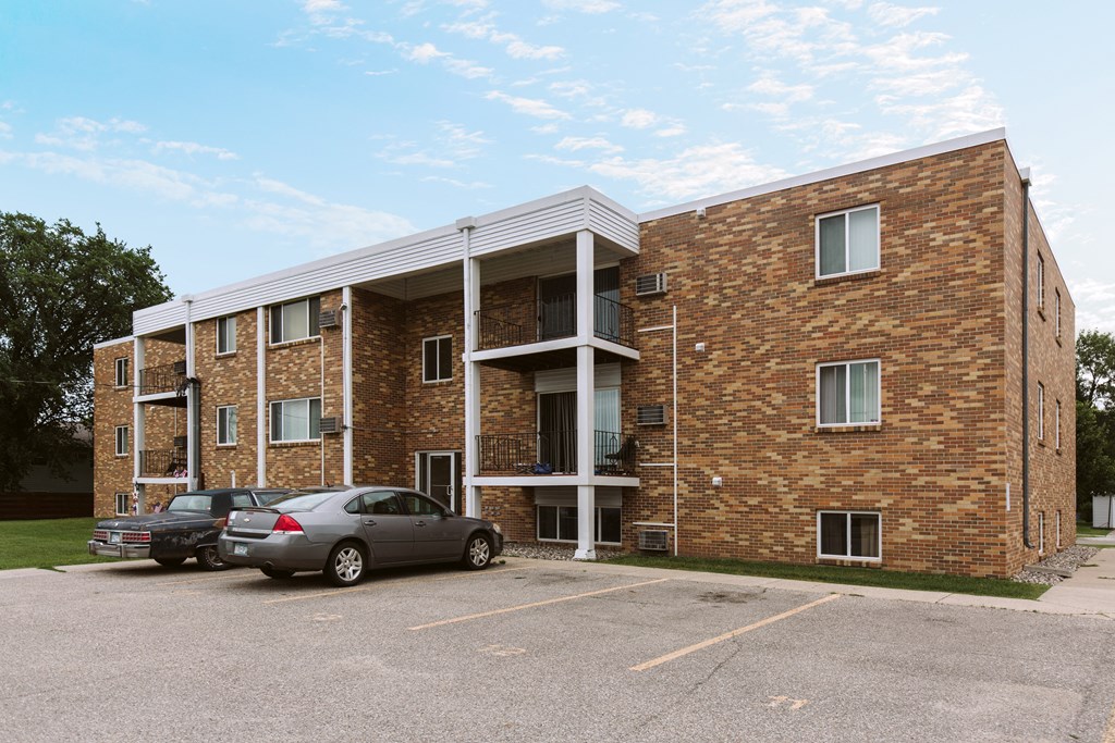 Grand Forks, ND Hoven Apartments | Exterior Grand Forks, ND Hoven Apartments. A brick apartment building with two cars parked in a parking lot
