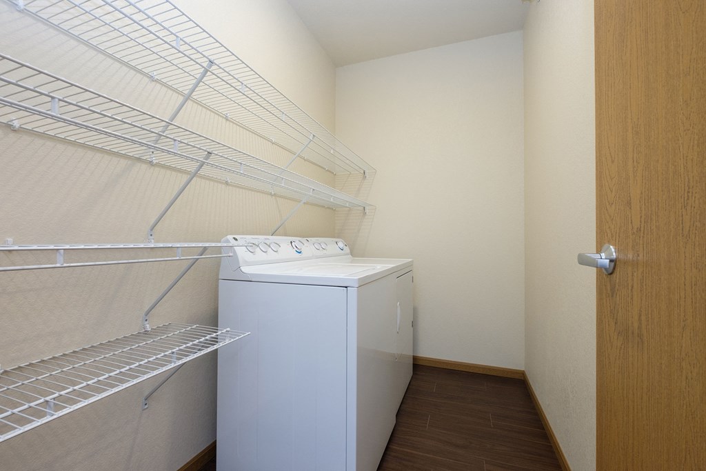 a laundry room with a washer and dryer and a door to a closet. Fargo, ND North Sky Apartments
