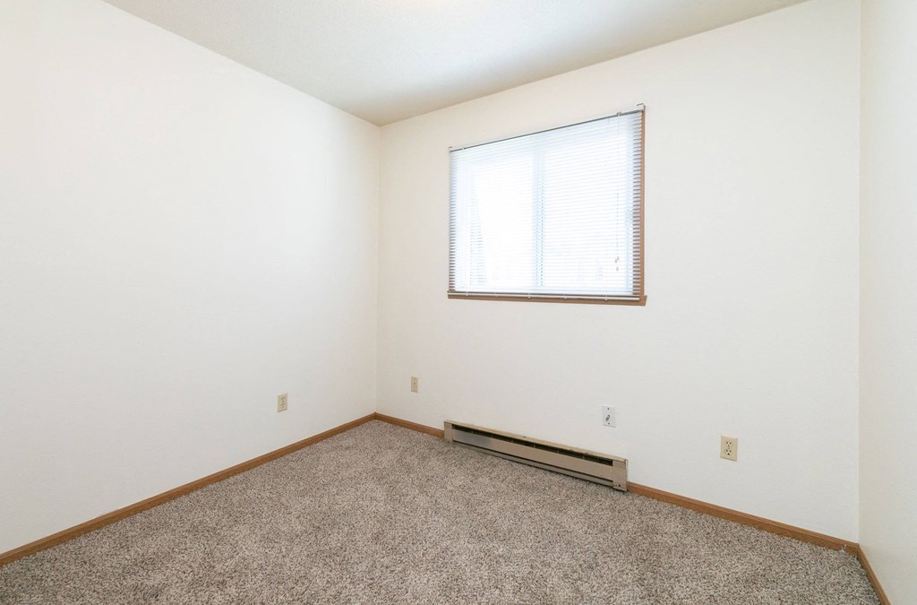 a bedroom with white walls and a window. Fargo, ND White Ridge Apartments