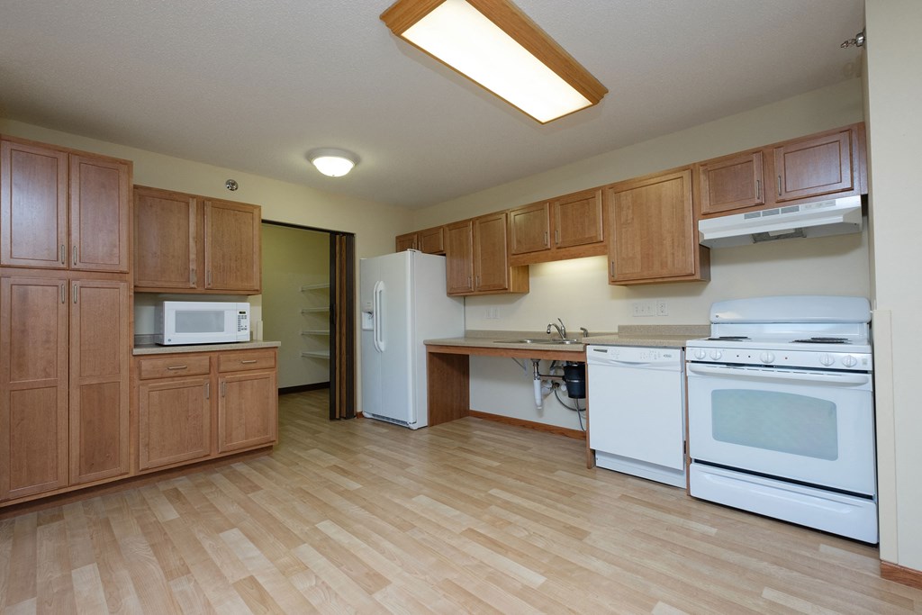 a kitchen with white appliances and wooden cabinets. Fargo, ND Crossroads Apartments