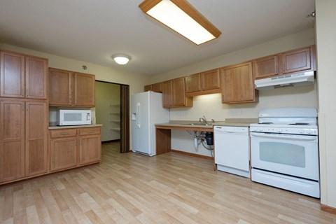 Fargo, ND Crossroads Apartments | Kitchen a kitchen with white appliances and wooden cabinets. Fargo, ND Crossroads Apartments