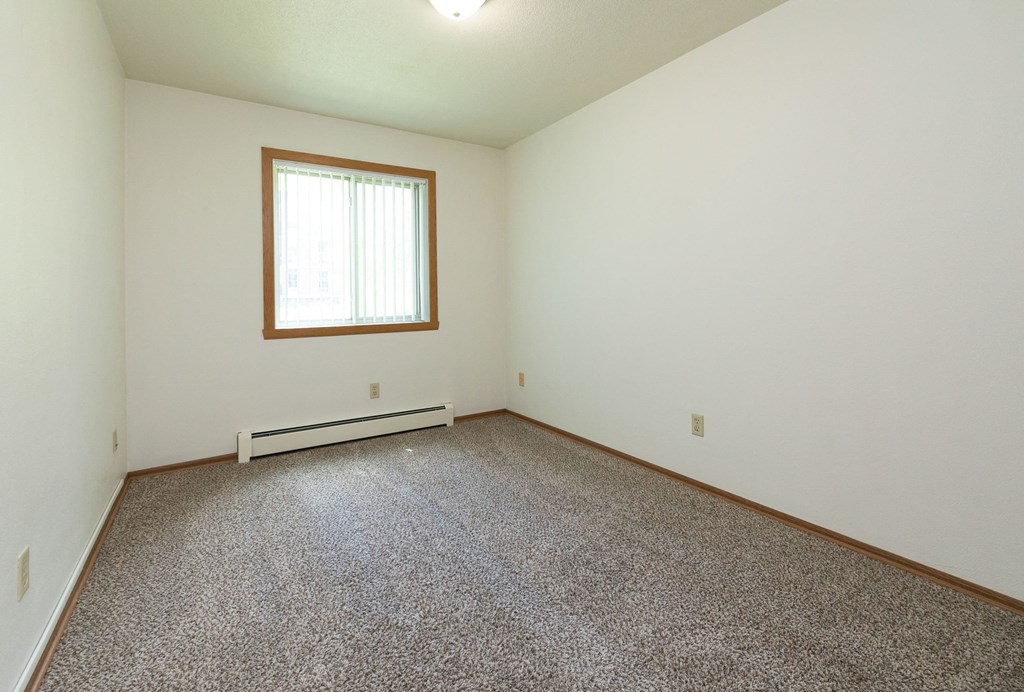 a bedroom with carpet and a window. Fargo, ND Islander Apartments