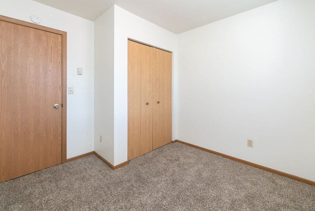 a bedroom with a closet door. Fargo, ND White Ridge Apartments