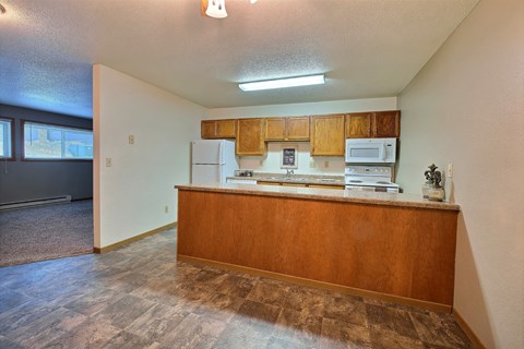 an empty kitchen with wood cabinets and a counter top. Fargo, ND Kennedy Apartments