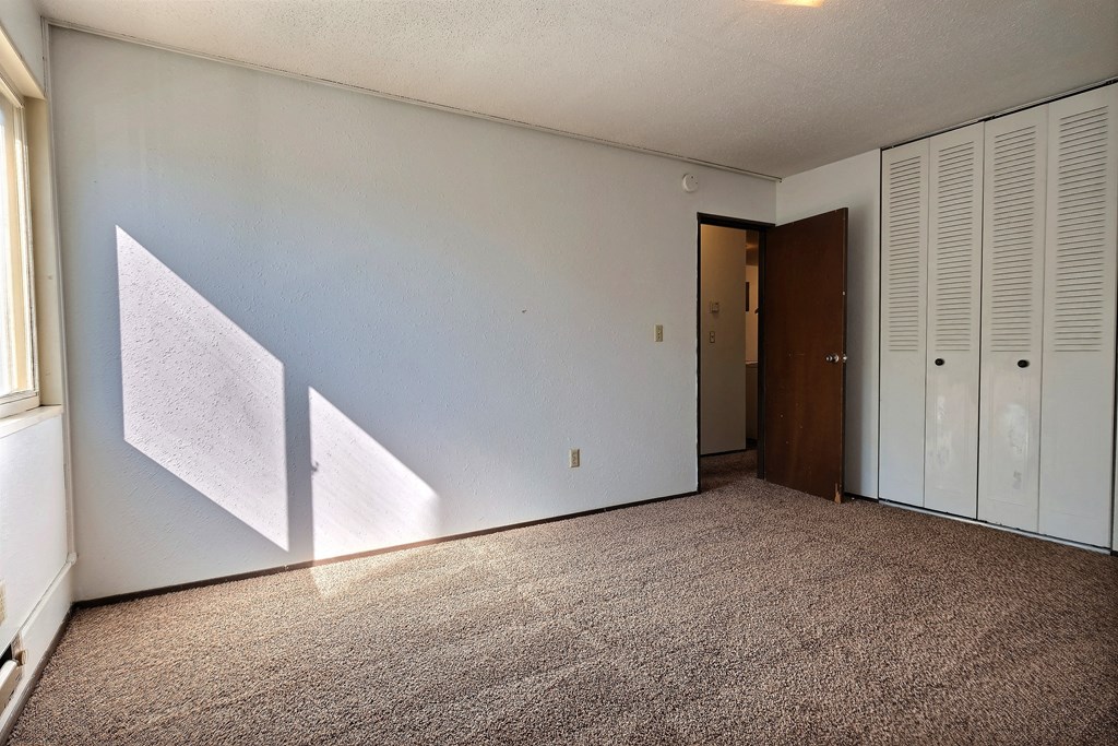 a bedroom with white walls and a carpet. Fargo, ND Kingswood Apartments