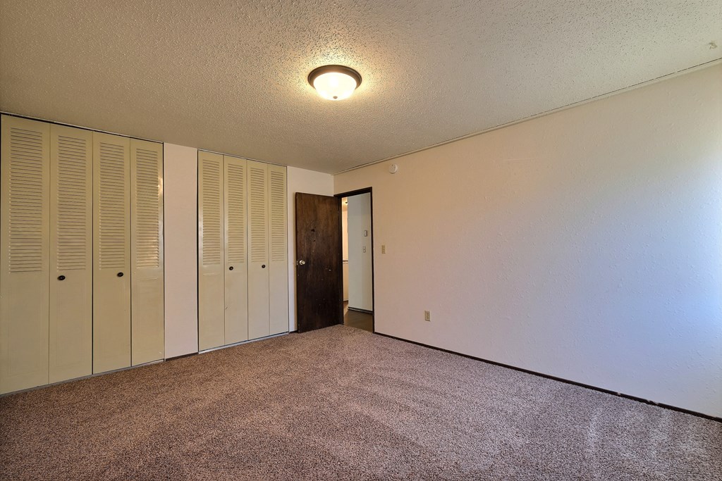 a bedroom with white walls and a door to a closet. Fargo, ND Kingswood Apartments