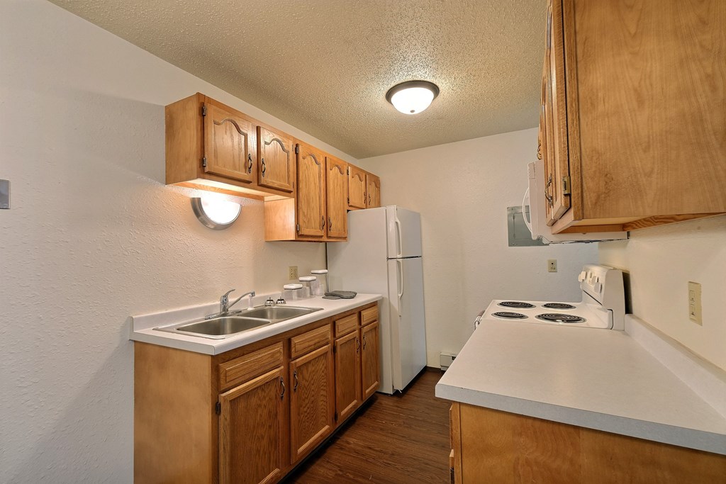 a kitchen with white appliances and wooden cabinets and a white refrigerator