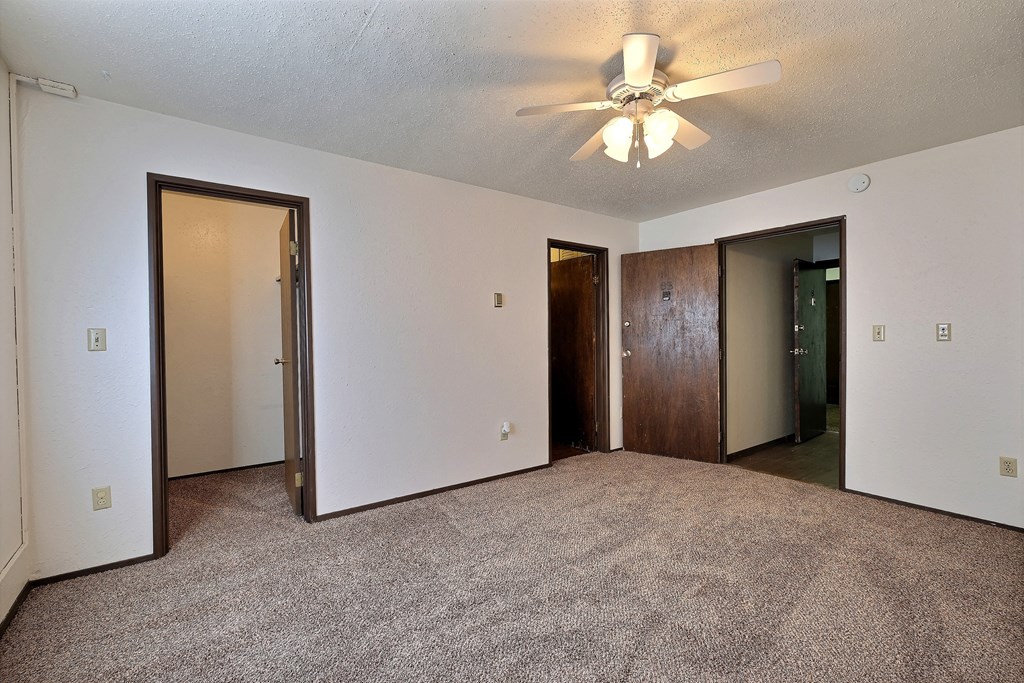 a bedroom with a ceiling fan and a closet. Fargo, ND Kingswood Apartments