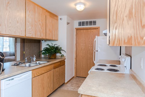 a kitchen with white appliances and wooden cabinets and a sink