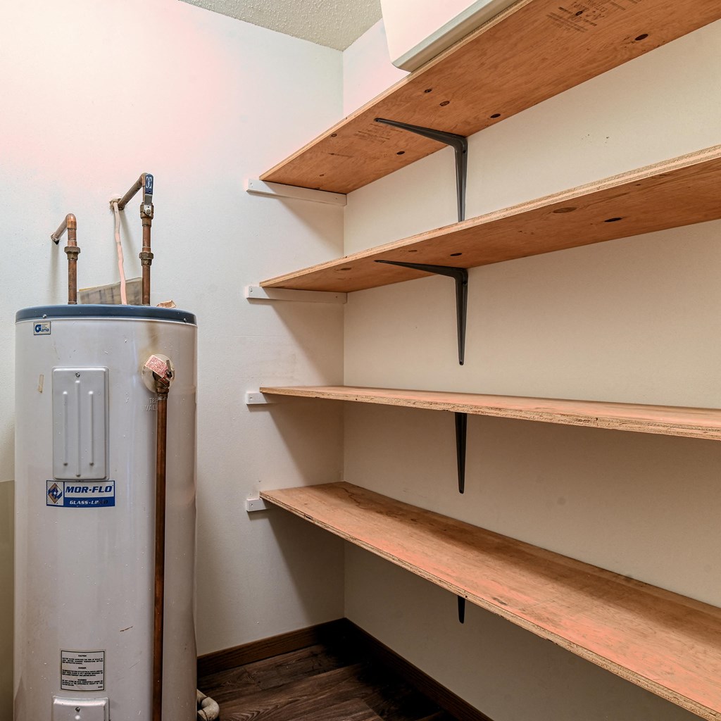Grand Forks, ND Madison Apartments. A closet with multiple shelves and a water heater.