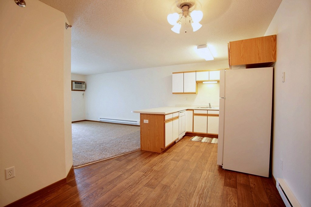 Akitchen and living room with wood flooring and white walls. Fargo, ND Lake Crest Apartments.