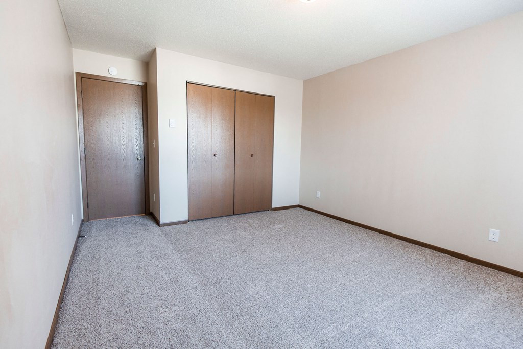 Grand Forks, ND Library Lane Apartments an empty bedroom with a closet and a carpeted floor