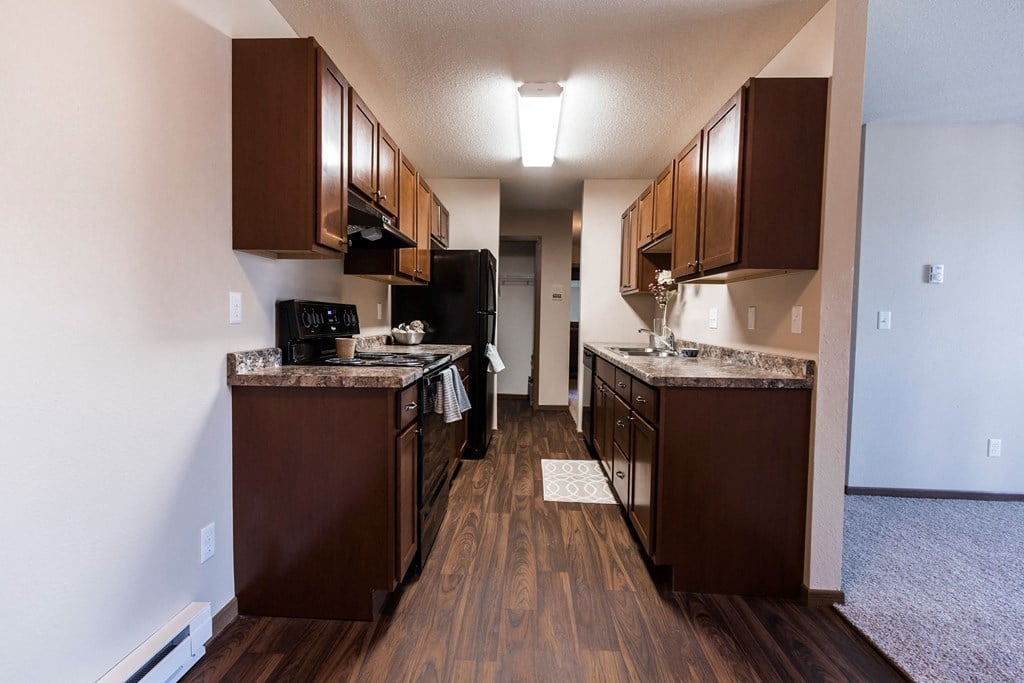 Grand Forks, ND Library Lane Apartments a kitchen with brown cabinets and a wood floor
