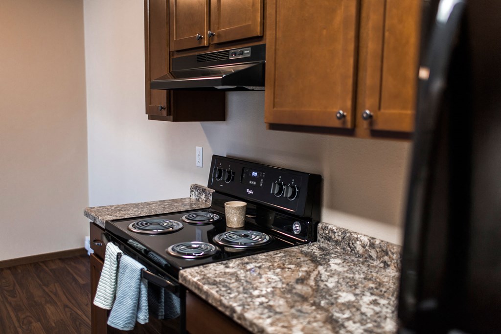 Grand Forks, ND Library Lane Apartments a kitchen with granite countertops and a black stove top oven