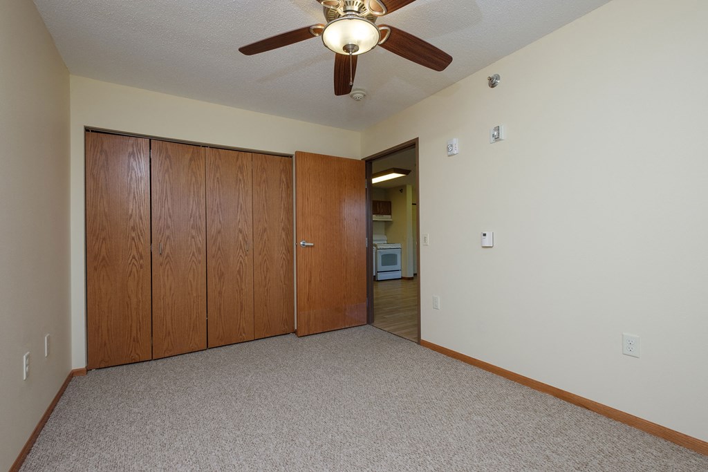 a bedroom with a closet and a door to a hallway. Fargo, ND Crossroads Apartments