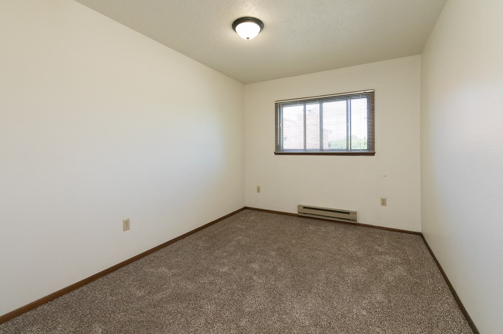 a bedroom with carpet and a window. Fargo, ND Maplewood Bend Apartments
