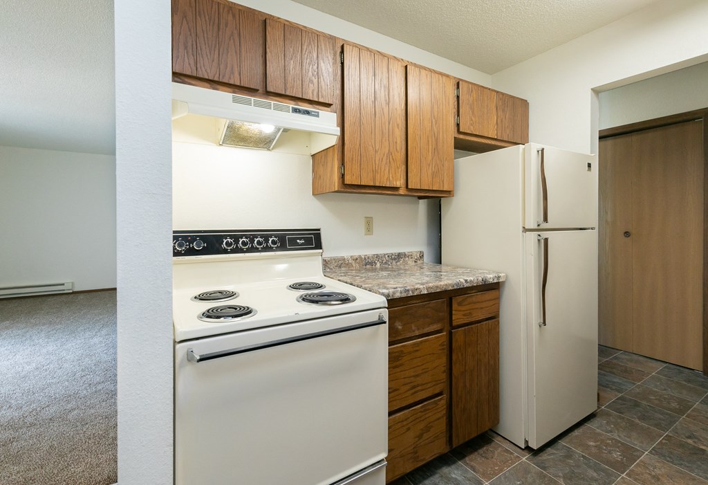 a kitchen with white appliances and wooden cabinets and a refrigerator. Fargo, ND Maplewood Bend Apartments