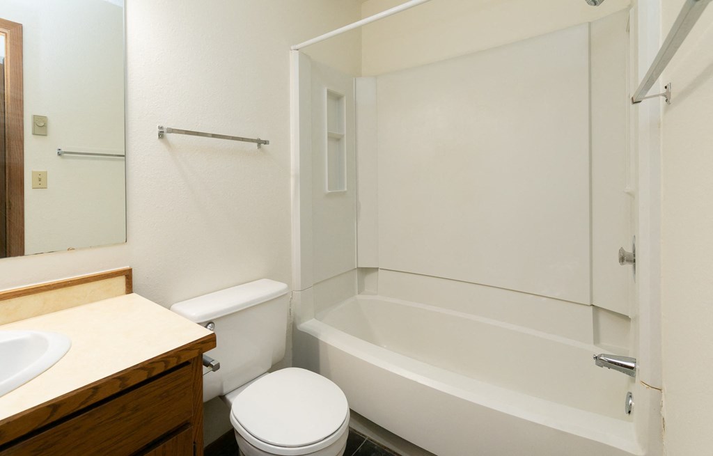 a bathroom with a toilet and a tub and a sink. Fargo, ND Maplewood Bend Apartments