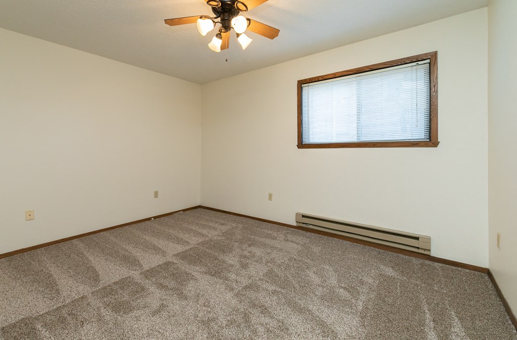 a bedroom with carpet and a ceiling fan. Fargo, ND Maplewood Bend Apartments
