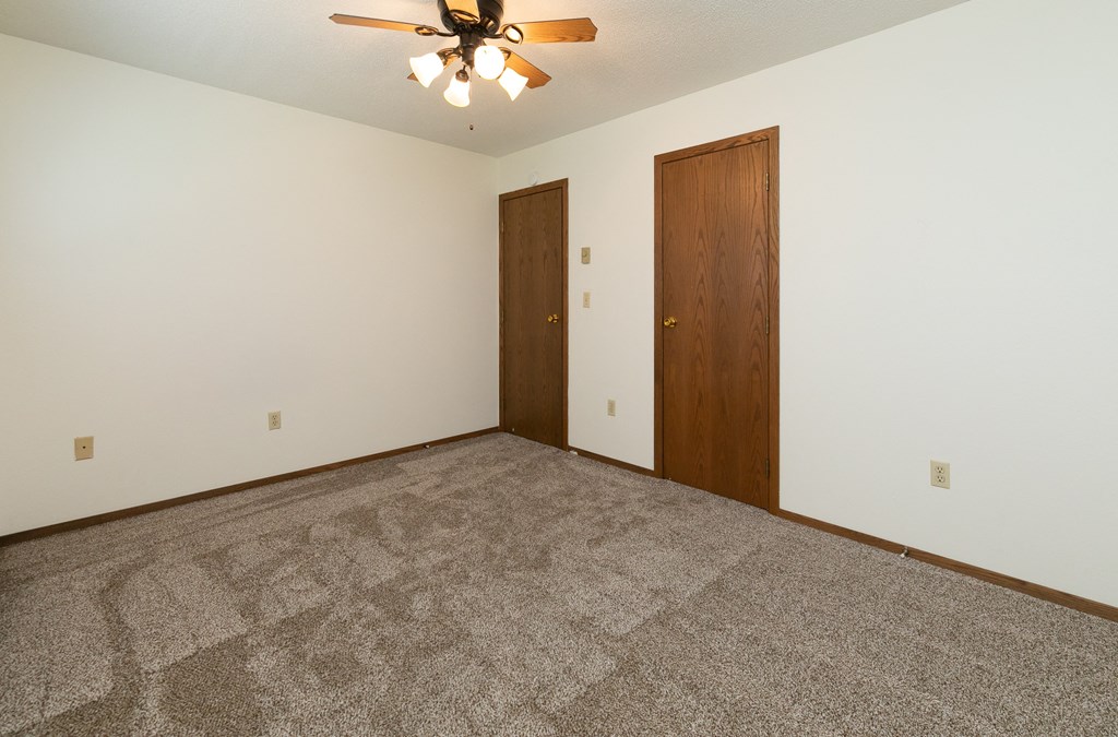 a bedroom with carpet and a ceiling fan. Fargo, ND Maplewood Bend Apartments