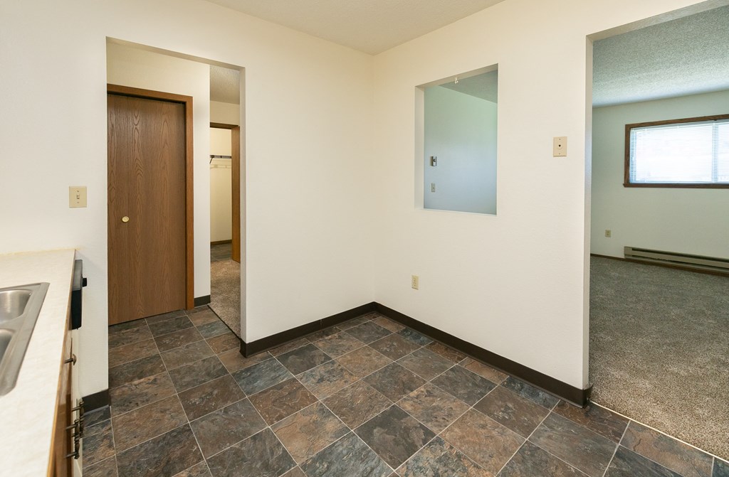 an empty kitchen and living room with a door to a hallway and a window. Fargo, ND Maplewood Bend Apartments