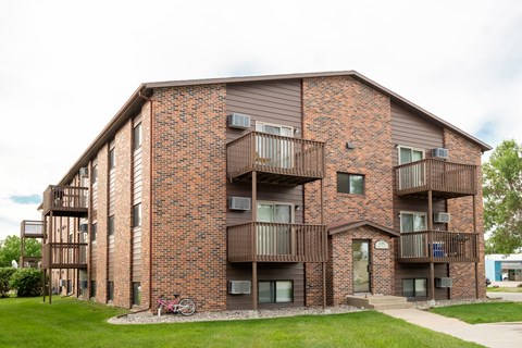 a brick apartment building with balconies and a bike parked outside. Fargo, ND Maplewood Bend Apartments