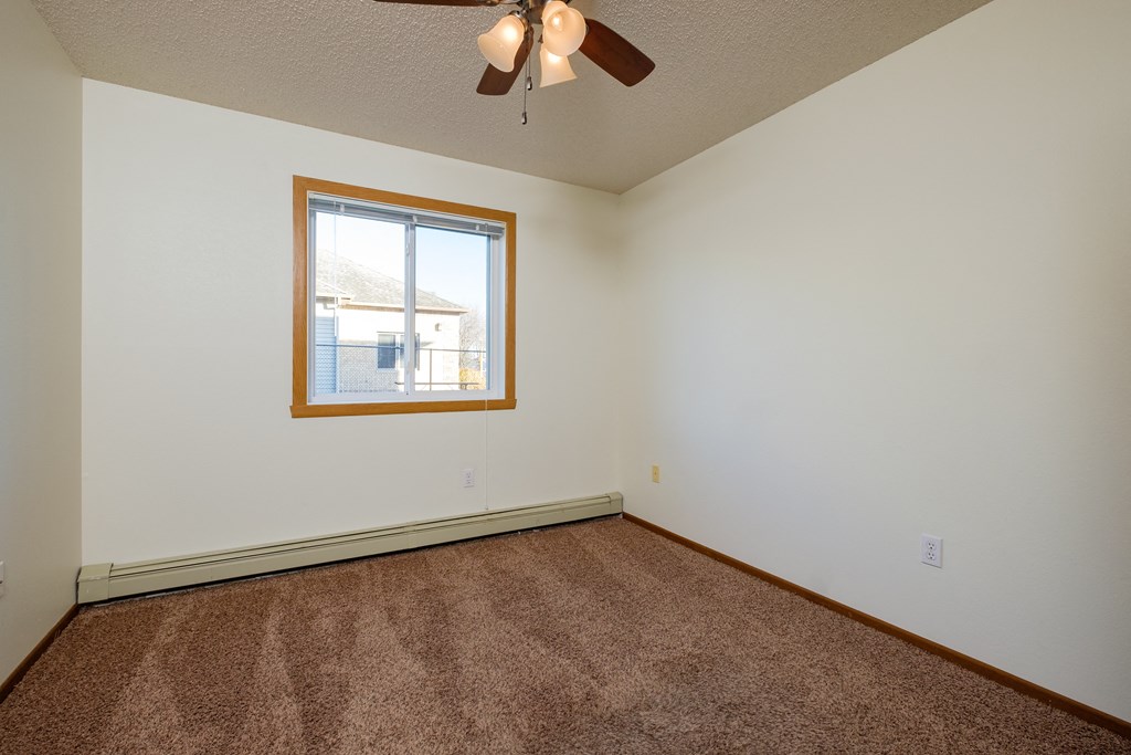 a bedroom with carpet and a window. Fargo, ND Maybrook Apartments