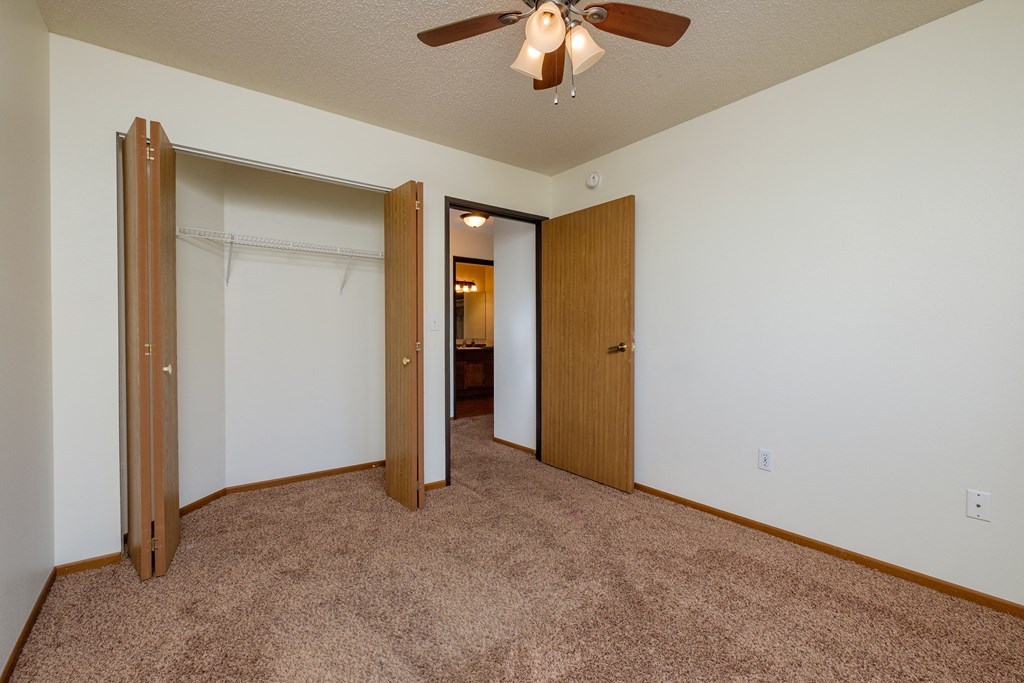 a bedroom with a ceiling fan and a closet. Fargo, ND Maybrook Apartments