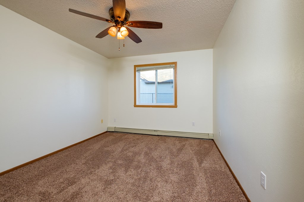 a bedroom with a ceiling fan and a window. Fargo, ND Maybrook Apartments