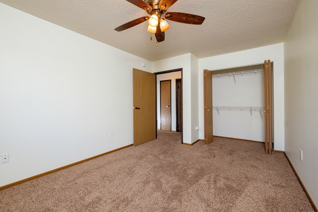 a bedroom with carpet and a ceiling fan. Fargo, ND Maybrook Apartments