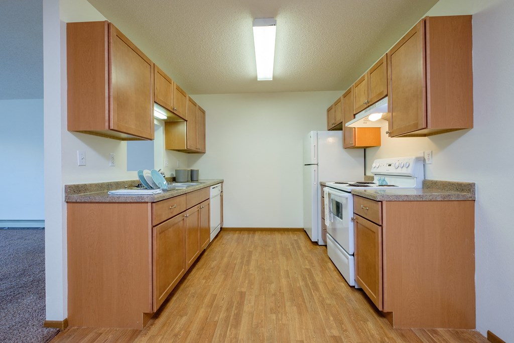 an empty kitchen with wooden cabinets and white appliances. Fargo, ND Maybrook Apartments