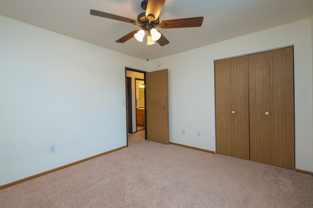 a bedroom with a ceiling fan and a closet. Fargo, ND Maybrook Apartments
