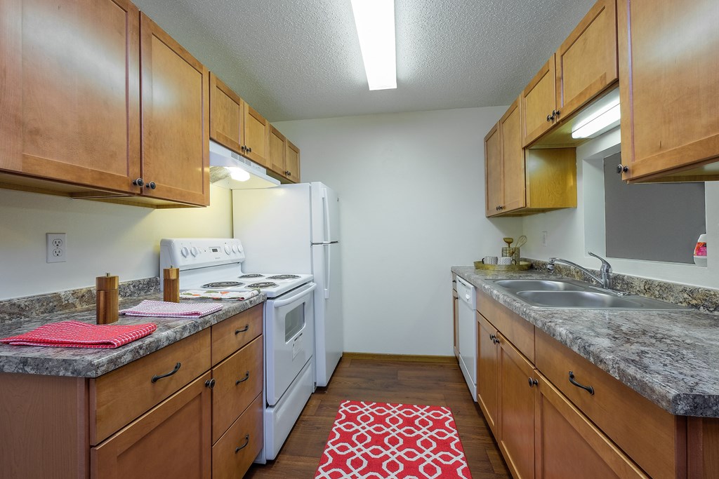 a kitchen with wood cabinets and white appliances and granite counter tops. Fargo, ND Maybrook Apartments