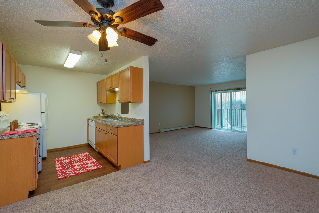 an empty kitchen and living room with a ceiling fan. Fargo, ND Maybrook Apartments