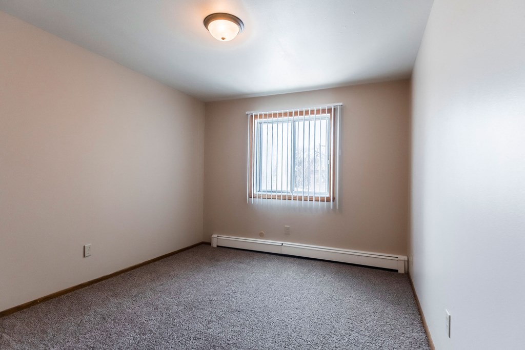 Grand Forks, ND Mayfair Apartments a bedroom with a window and carpeted floors