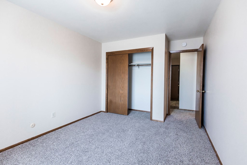 Grand Forks, ND Mayfair Apartments a bedroom with white walls and carpet