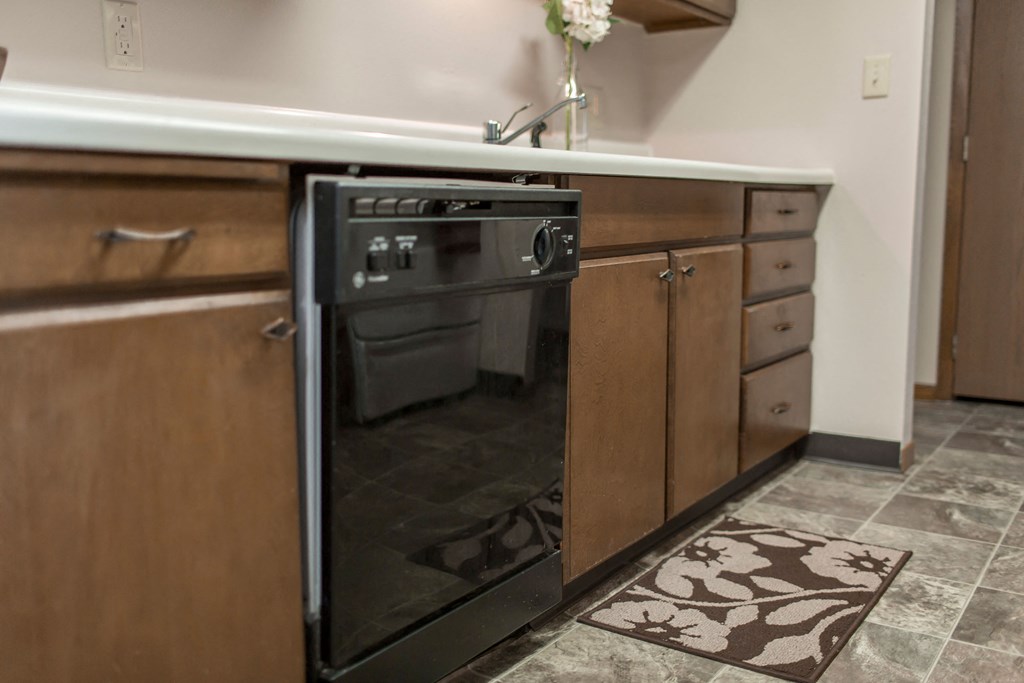 Grand Forks, ND Mayfair Apartments a kitchen with wooden cabinets and a black dishwasher