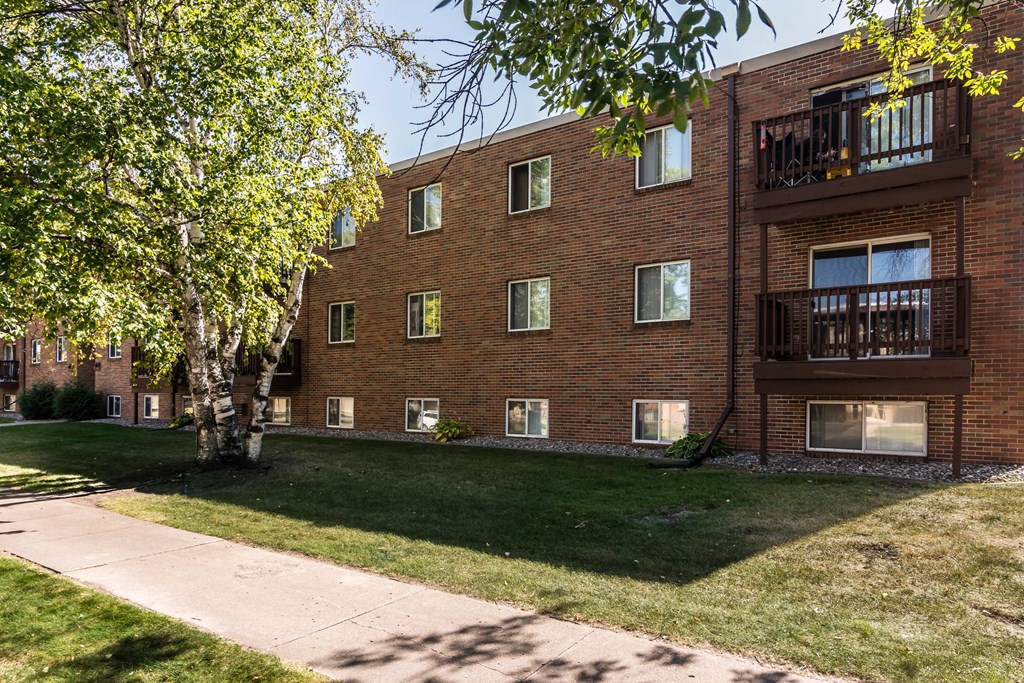 Grand Forks, ND Mayfair Apartments. An exterior of a three level apartment building with a sidewalk out front.