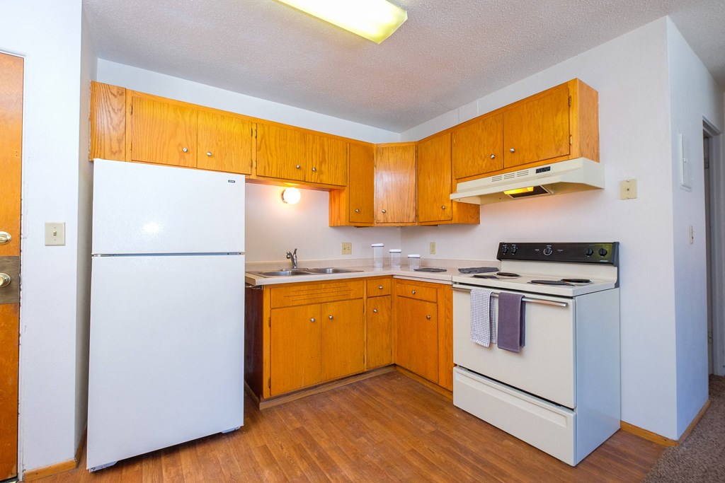 an empty kitchen with white appliances and wooden cabinets. Fargo, ND Morningside Apartments