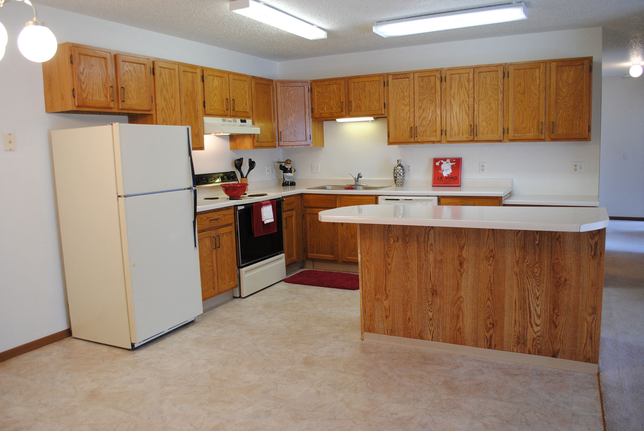 an empty kitchen with white appliances and wooden cabinets