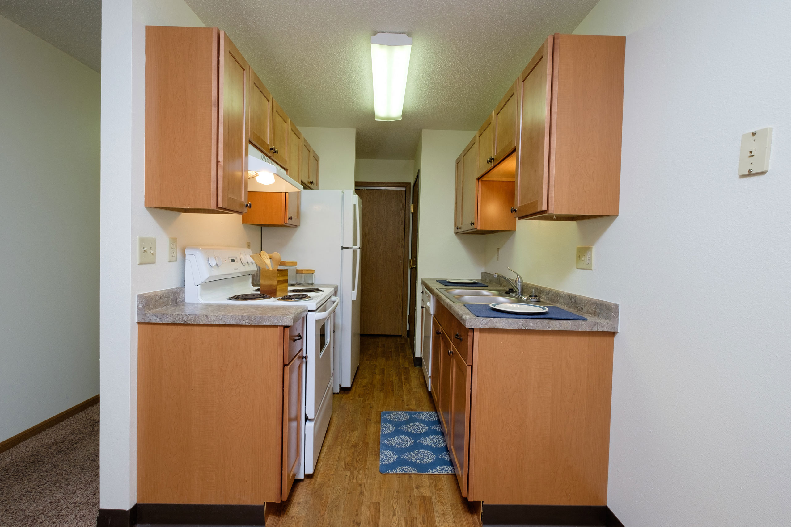a kitchen with white appliances and wooden cabinets. Fargo, ND Monticello Apartments