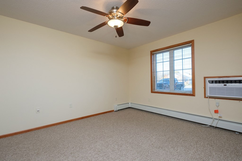 a bedroom with a window and a ceiling fan. Fargo, ND Crossroads Apartments