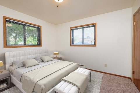 a white bedroom with a bed and two windows. Moorhead, MN Northwood Apartments
