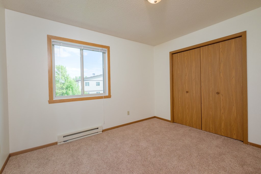 Empty bedroom with a window and a closet. Fargo, ND 58013 Oak Court Apartments