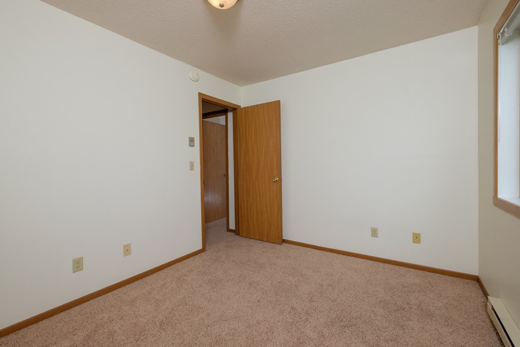 Bedroom with white walls and a door to a closet. Oak Court Apartments, Fargo