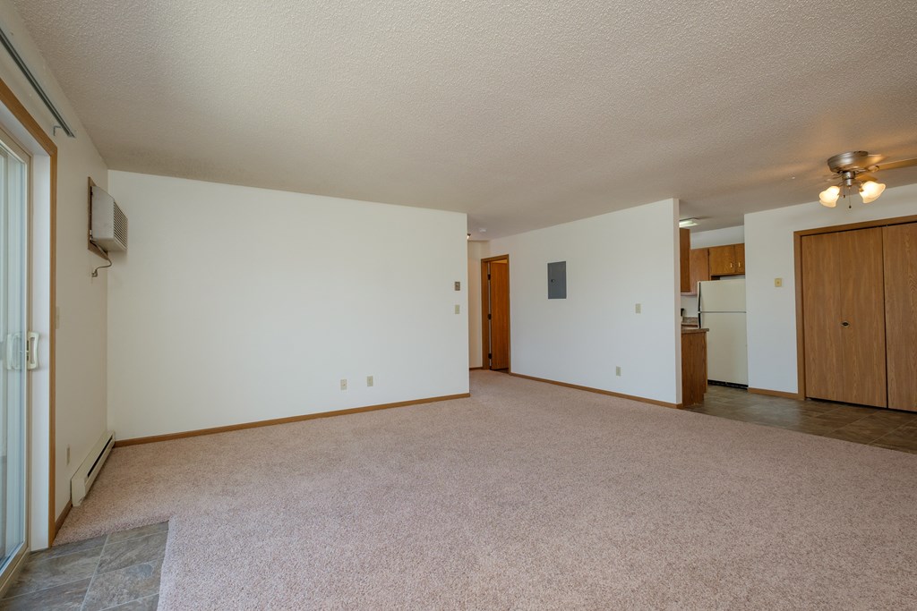 Living room of an empty house with white walls and a beige carpet, Oak Court Apartments, ND 58103